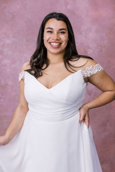 a woman in a white dress posing for the camera with her hands on her hips