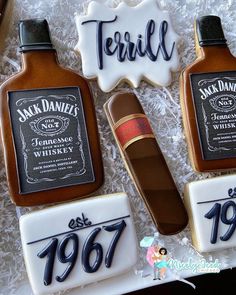 three decorated cookies in the shape of whiskey bottles and cigars with writing on them