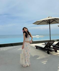 a woman standing on top of a roof next to an umbrella and chair with the ocean in the background