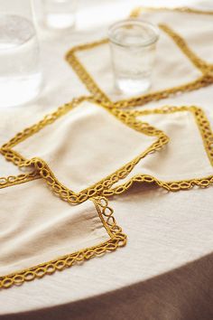 three napkins with gold chains on them sitting on top of a white table cloth