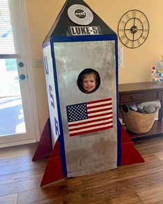 a cardboard rocket ship with a child's face in the center and an american flag on it