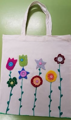 a white bag with flowers on it sitting on a green table next to a wall