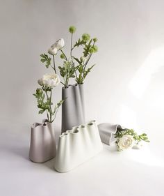 three vases with flowers in them on a white surface