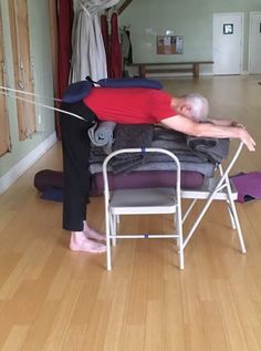 a woman stretching out on her chair in the middle of a room with yoga mats