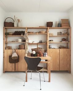 a chair sitting in front of a wooden book shelf filled with books and baskets on top of it