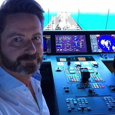 a man sitting in the cockpit of a plane looking at the camera with an airplane control panel behind him