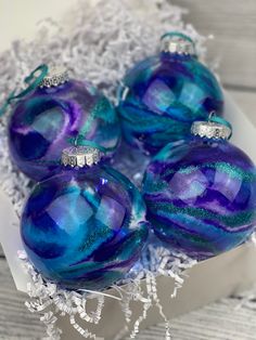 four blue and purple ornaments in a white box