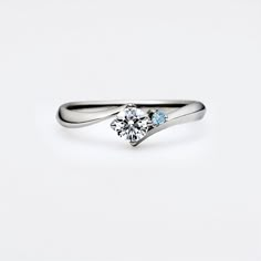 a white gold ring with two blue stones on the top and one diamond in the middle