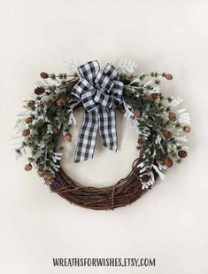 a wreath with pine cones and snowflakes is hung on the wall next to a white wall