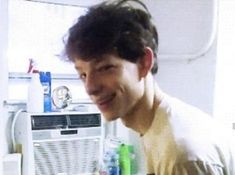 a man standing in front of an open refrigerator with water bottles and toothbrushes on it