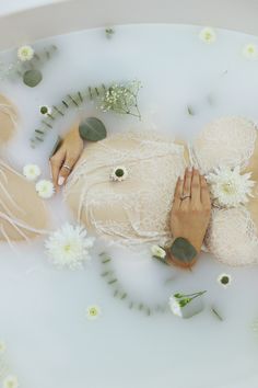 a woman laying in a bath with flowers on the side