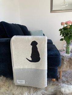 a dog is sitting on the floor next to a blue couch and vase with flowers