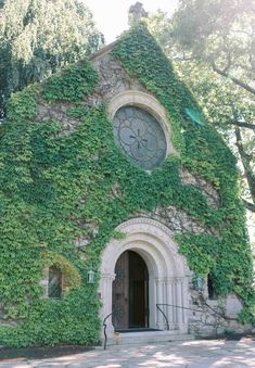 an old church covered in ivy with a clock on it's front door and windows