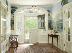 an entry way with a painting on the wall and two doors leading to another room