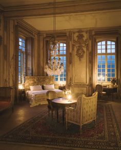 a fancy bedroom with chandelier, bed and two chairs next to each other