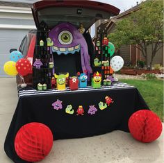 a table with decorations on it in front of a car and some balloons around it