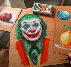 a drawing of a clown with colored crayons on the table next to it