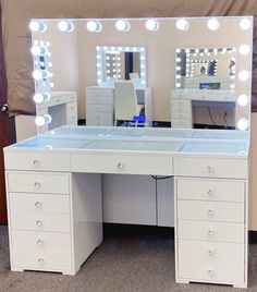 a white vanity with lighted mirrors and drawers