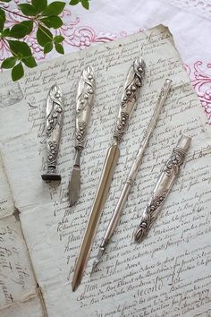 four antique silverware sitting on top of an old paper