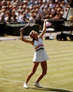 a female tennis player serving the ball in front of an audience at a tennis match