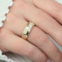 a close up of a person's hand wearing a ring with three diamonds on it