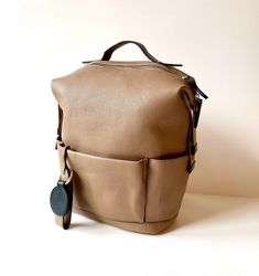 a tan leather bag sitting on top of a white table