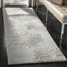 a living room with a white rug on the floor next to a couch and window