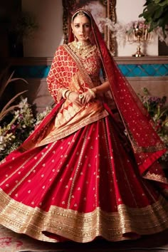 a woman in a red and gold bridal gown with her hands on her hips