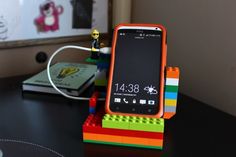 an orange cell phone is sitting on top of legos and it's charging