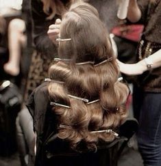 a woman is getting her hair done at the same time as others are in the background