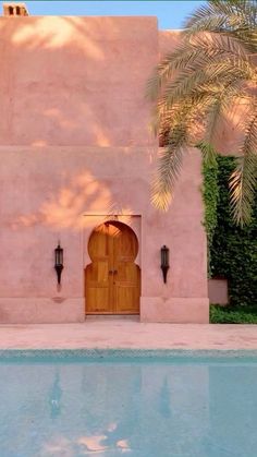 a house with a pool and palm trees in front of the door that leads to it