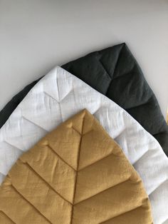 three folded napkins sitting on top of each other next to an orange and black piece of cloth