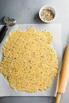 an uncooked pizza crust on a cutting board next to a bowl of seasoning