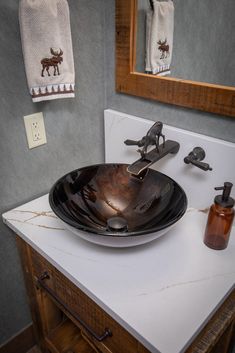 a black bowl sink sitting on top of a white counter next to a bathroom mirror