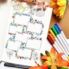 an open planner with flowers and markers next to it