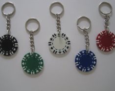 four different colored poker chip keychains on a white surface with one red, one blue and one green