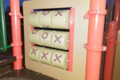 an outdoor play area with pink and green poles, orange posts and two xo signs on the wall