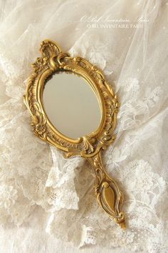 a gold mirror sitting on top of a white lace covered table