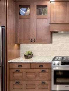 a kitchen with wooden cabinets and stainless steel stove top oven in the center, surrounded by white marble countertops