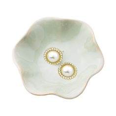 a pair of pearl and gold earrings on a white flower shaped dish with pearls in the center