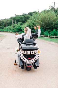 a bride and groom are riding on a motorcycle together in the middle of the road