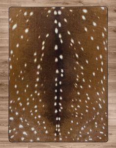 a brown and white deer skin rug with spots on the fur, in front of a wooden floor