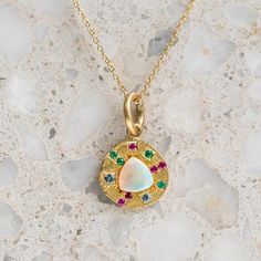 Our pebble collection of raw, rough, beaten metals set with precious gems. Perfectly imperfect and all one of a kind. A crystal opal is surrounded by pink sapphires, emeralds and aquamarines and is set into a pebble disc necklace. Pebble measures 13.5mm round approx. Pendant weighs 4.8g approx. If ordering with a chain, the chain measures 45cm. Please note if ordering the white gold it is raw with a matte finish and not rhodium plated. Ethiopian Opal Gemstone Pendant Jewelry, Opal Multi-stone Pendant Necklace, Gemstone Jewelry With Ethiopian Opal Round Pendant, Forest Necklace, Diamond Drop Necklace, Initial Disc Necklace, Pebble Necklace, Diamond Bar Necklace, Snowflake Necklace