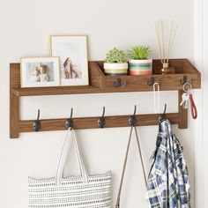 a coat rack with hooks and two purses hanging from it's sides next to a white wall