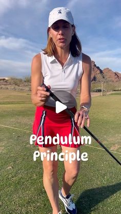 a woman holding a golf club on top of a green field