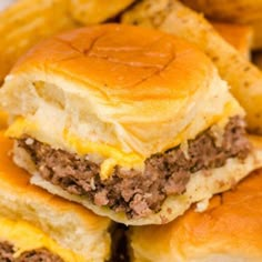 three cheeseburger sliders stacked on top of each other with fries in the background