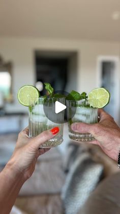 two people holding up glasses filled with green liquid and lime slices on the rims