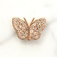 a gold butterfly brooch sitting on top of a white marble surface with lots of diamonds