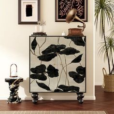 a black and white cabinet sitting next to a potted plant on top of a wooden floor