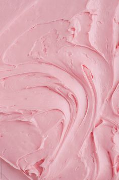 a close up view of pink icing on a cake